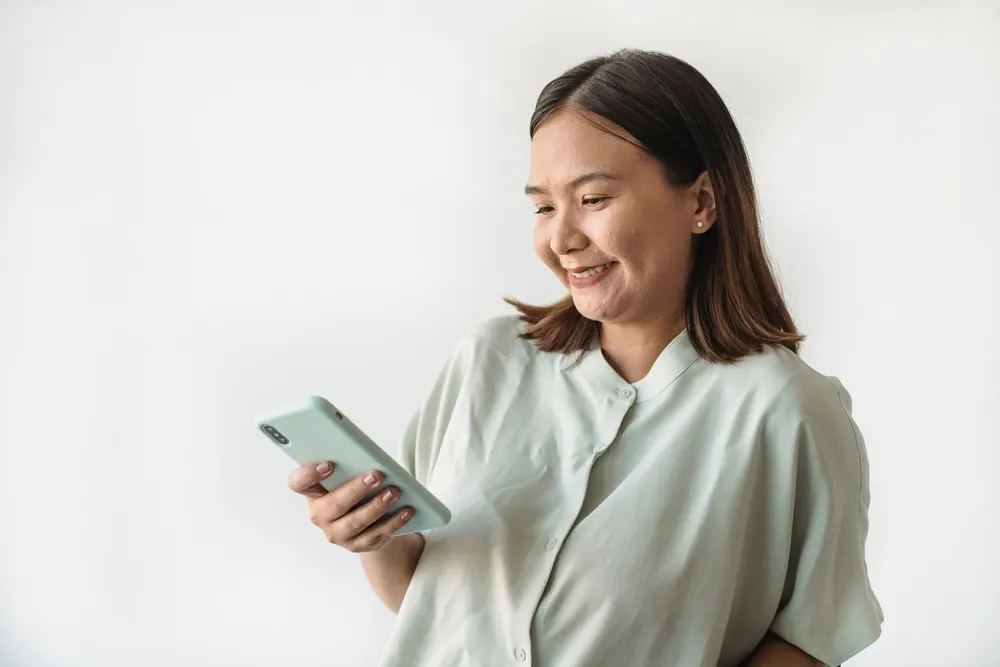 Mujer sonriendo mientras usa el celular