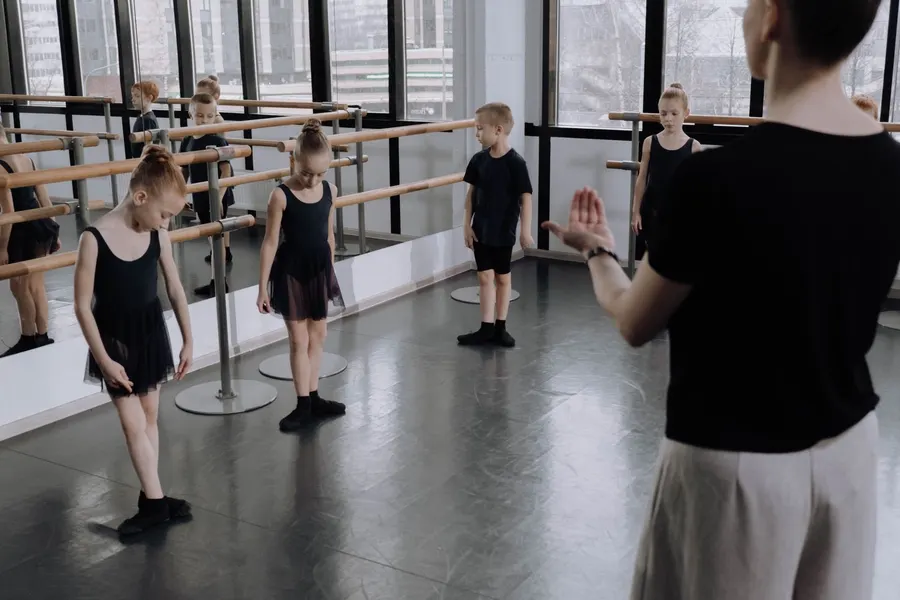 Profesora de ballet con alumnas en la barra